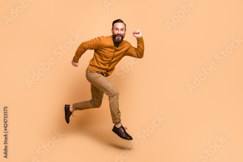 Full body profile photo of cheerful handsome guy toothy smile look camera isolated on beige color background