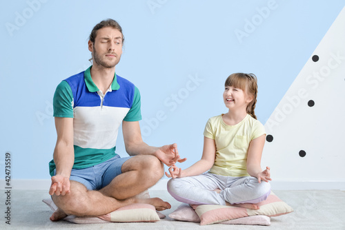 Portrait of meditating father and daughter at home