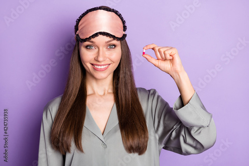 Portrait of lovely healthy cheerful girl wear pajama holding in hand drowse pill therapy isolated over violet purple color background