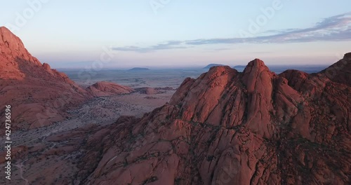 4K sunrise aerial footage of savanna, famous red granite Spitzkoppe Peak and Pontok Mountains in central Namibia between interior town Usakos and Atlantic west coast, southern Africa
