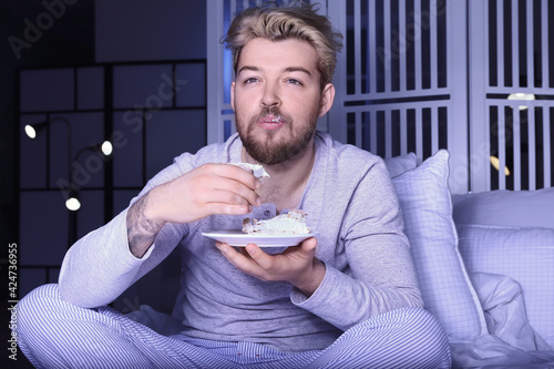 Young man eating cake while...