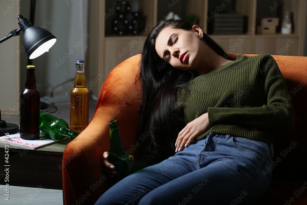 Drunk young woman at home in evening. Concept of addiction to alcohol - obrazy, fototapety, plakaty 