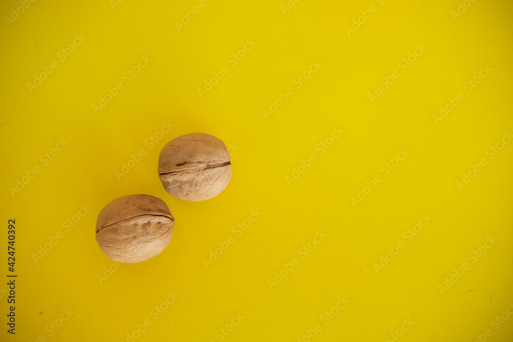 Two walnut trees on a yellow solid background. Food background. Kitchen. Two walnut trees on a yellow solid background. Food background. Kitchen.