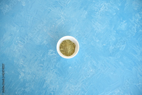 Top view of organic matcha green tea in a bowl and matcha powder. Blue cheerful background.