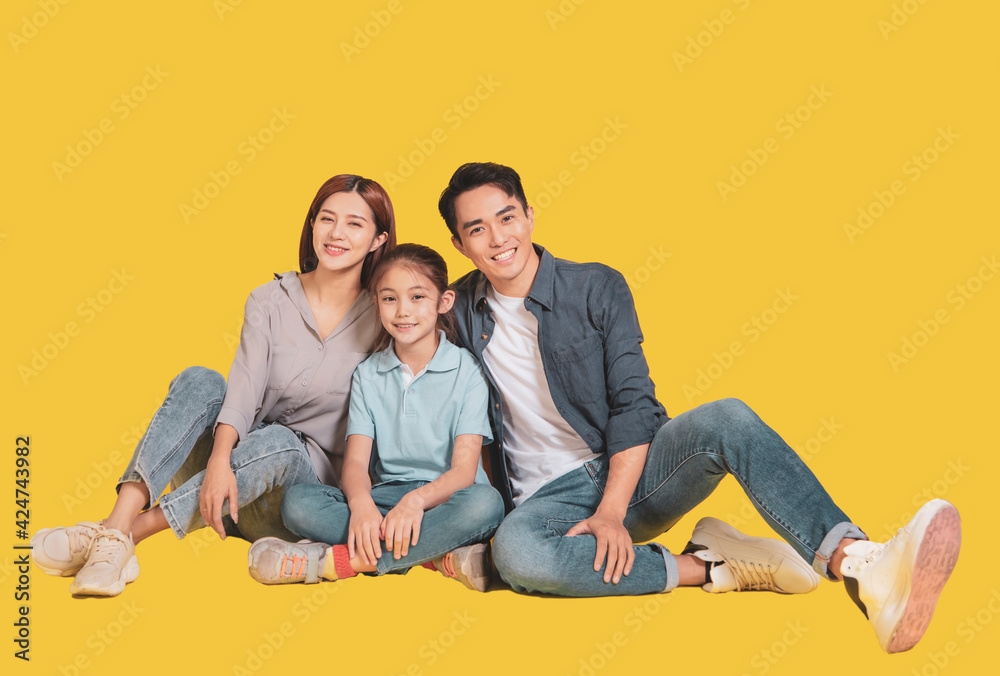 Happy Asian young family with one child sitting and smiling at camera isolated on yellow Happy Asian young family with one child sitting and smiling at camera isolated on yellow