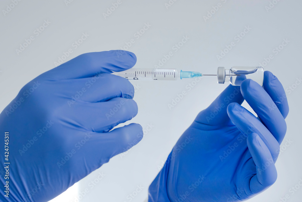 Doctor hands holding a vaccine bottle and syringe,beginning of worldwide mass vaccination for coronavirus COVID-19,influenza or flu,world immunization concept. Selective focus