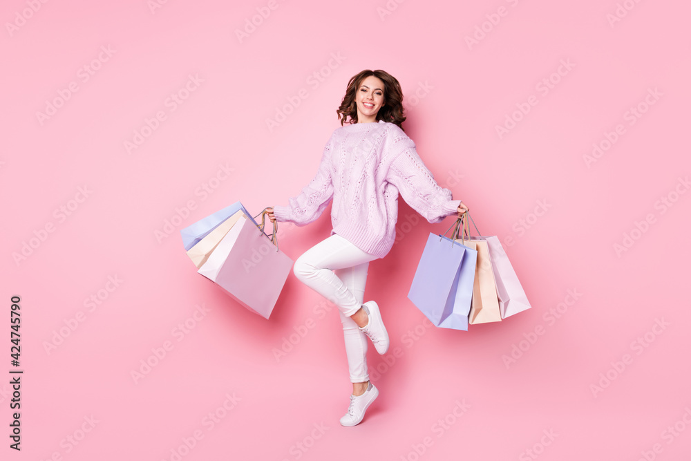 Photo of funny adorable young woman knitted sweater holding colorful bargains isolated pastel pink color background