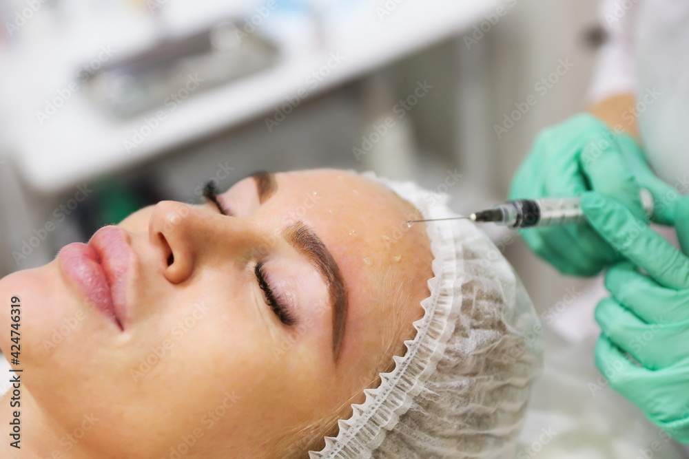 beautician applies anti-wrinkle medicine to woman's face beautician applies anti-wrinkle medicine to woman's face