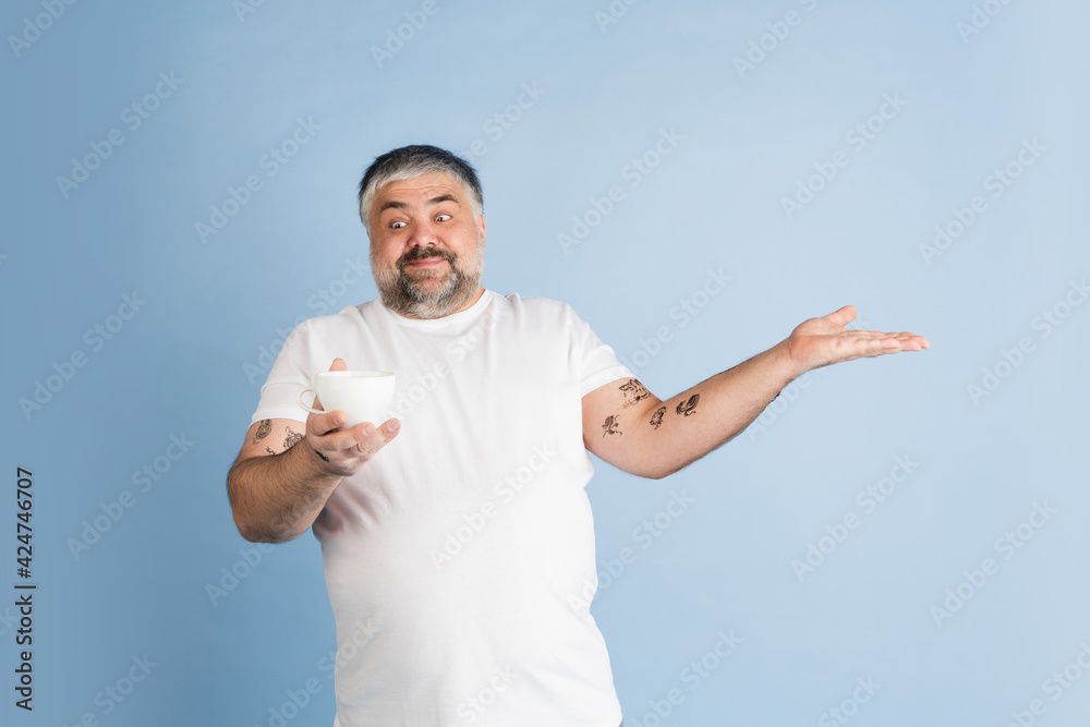 Handsome caucasian plus size male model isolated on blue studio background. Concept of inclusion, human emotions, facial expression Handsome caucasian plus size male model isolated on blue studio background. Concept of inclusion, human emotions, facial expression