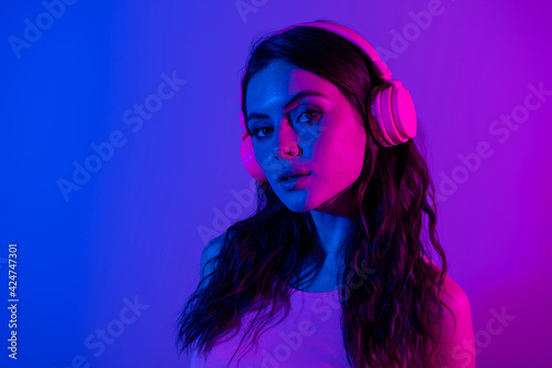 Photo of beautiful lovely stunning elegant woman listen music in headphones isolated on blue glowing neon color background