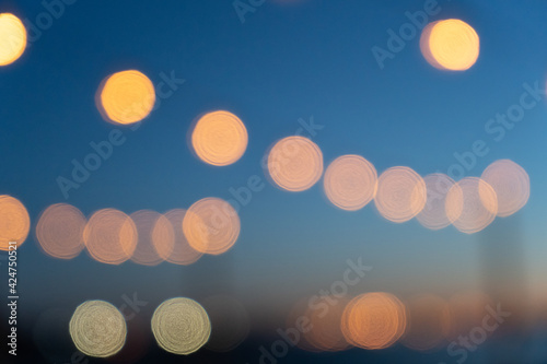 Close up of the glowing light bulbs at the beach cafe terrace. Sun is setting in the blurry abstract background.