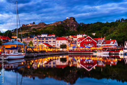 Halden, Norway. View of the illuminated houses and yachts with Fredriksted fortress at the background in Halden, Norway in the evening with cloudy sunset sky in summer