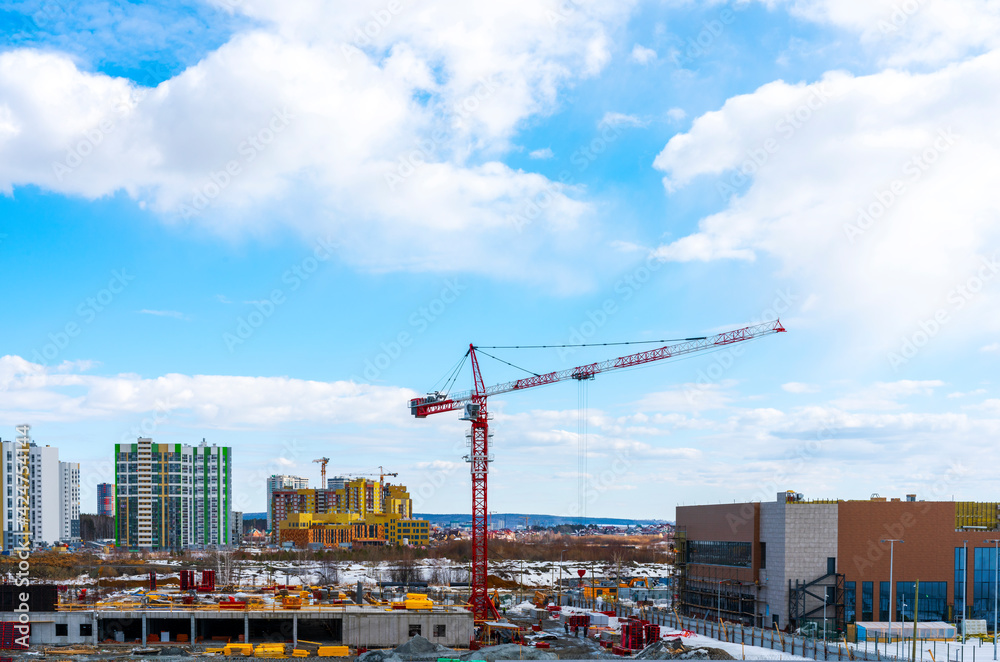 Construction of a new multistory building in the city, red construction crane on a blue cloudy sky background, construction site, New High-Rise Buildings