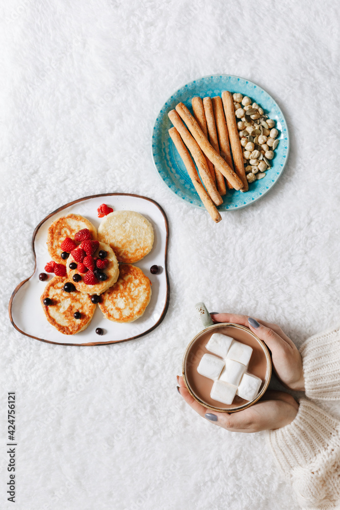 Woman holding a cup with marshmallows on background with cheesecakes and snacks. Flat lay. Lunch concept
Woman holding a cup with marshmallows on background with cheesecakes and snacks. Flat lay. Lunch concept