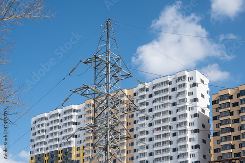 High voltage power line support in front of the residential high-rise building © ilyaska