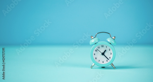 Fototapeta Naklejka Na Ścianę i Meble -  Blue small alarm clock on a blue background.