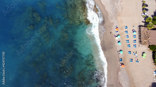Beach view from drone perspective. People have a rest and a sunbathe using umbrellas near a beach at the Caribbean.