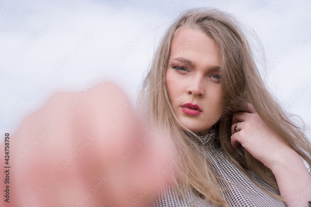 Beauty portrait of a young blond girl in a vintage dress. She is posing on a sandy landscape with harsh sun.