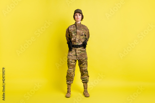 Full body photo of pretty focused person standing hold hands behind back isolated on yellow color background