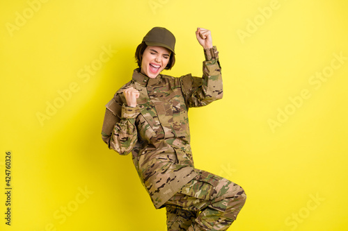 Portrait of delighted positive lady closed eyes fists knee up open mouth shout yes isolated on yellow color background