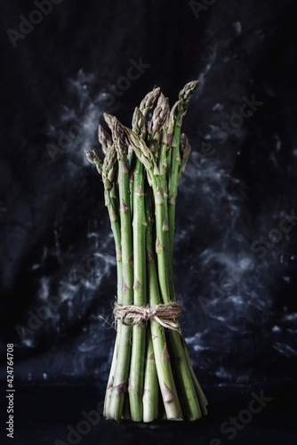 Photos A bunch of asparagus on black background, close up, still life photography