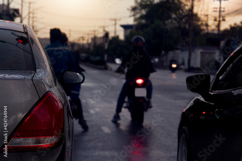 Luxury of brown car stop on the asphalt road. On the surface of the car is full of rain drops. Evening moments when the floor was wet with water and the blur of motorcyclists.