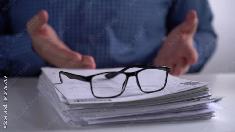Stack of Papers and Glasses on the Background of the Manager. Manager Explains and Leads with Hands. Close-up. Stack of Papers and Glasses on the Background of the Manager. Manager Explains and Leads with Hands. Close-up.