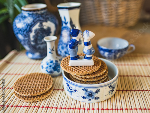 Traditional Dutch stroopwafel with syrup and typical Dutch blue. Porcelain figurines of kissing boy and girl in national Dutch costumes