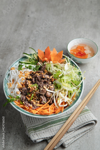 Foto A large bowl of traditional South Vietnamese noodle dish called Bun Bo Nam Bo with beef, noodles, fresh herbs, pickled vegetables and fish sauce
