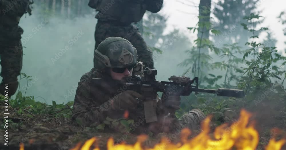 Special Forces soldiers in action. Elite squad moves through fire and smoke in forest Special Forces soldiers in action. Elite squad moves through fire and smoke in forest