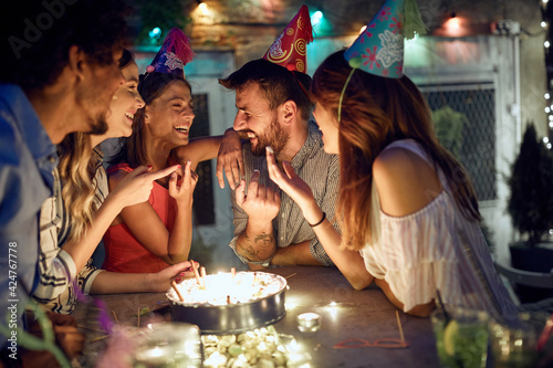 Photography Group of cheerful friends trying birthday cake at the open air party