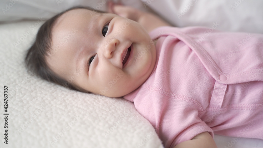 asian baby infant laying down on white soft bed happy and smile. 3 months old baby facial expression. asian baby infant laying down on white soft bed happy and smile. 3 months old baby facial expression.