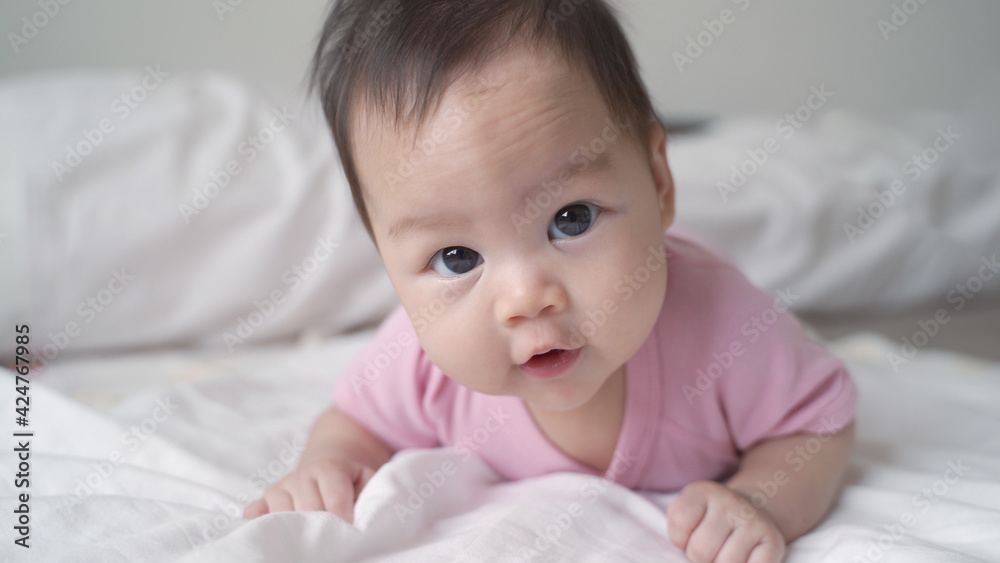 happy asian baby infant learning to crawl on white soft bed. 3 months old baby facial expression. lovely and smile baby.