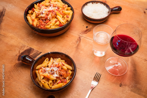Penne all Arrabiata Pasta or Noodle Dish with Red Wine, Parmesan Cheese on a Rustic Table