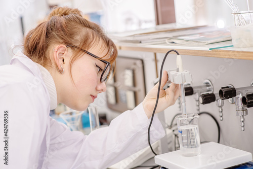 In a chemical laboratory  a girl laboratory assistant drips a solution into a measuring beaker with a special pipette