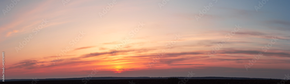 Panorama of red sunset. The yellow sun disappeared behind striped clouds Panorama of red sunset. The yellow sun disappeared behind striped clouds