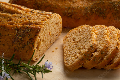 Fresh traditional baked loaf of italian rosemary bread and slices and a twig of fresh rosemary close up 