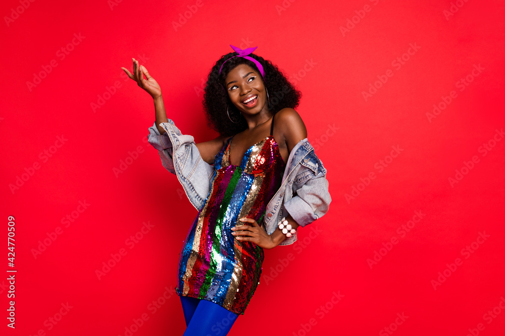 Photo of charming pretty wavy dark skin lady wear pin up outfit dancing looking empty space isolated red color background Photo of charming pretty wavy dark skin lady wear pin up outfit dancing looking empty space isolated red color background
