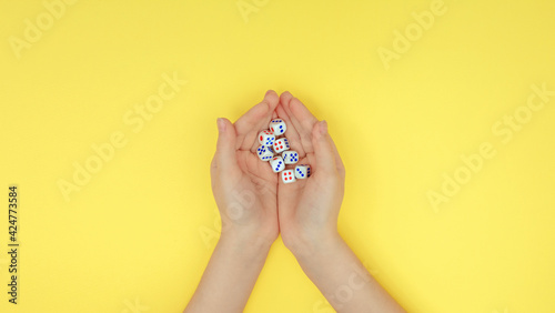 hands with dice on a yellow background