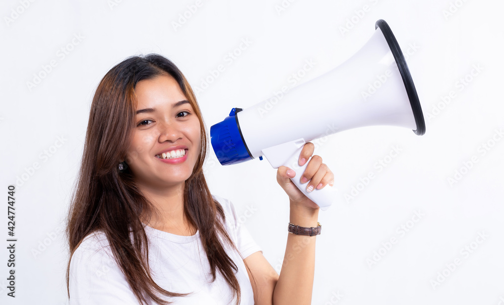 Smiling young woman holding megaphone isolated on gray background. Smiling young woman holding megaphone isolated on gray background.