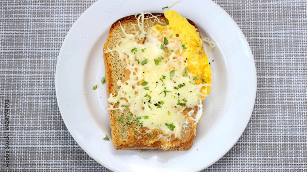Hot sandwich with egg, cheese and herbs on a plate.