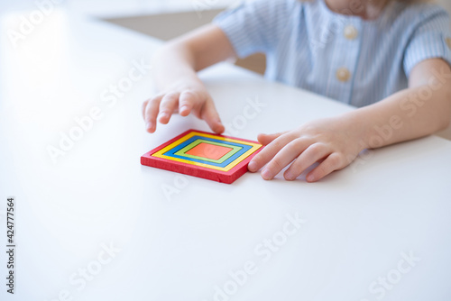 A child holds a Montessori educational game on a white table