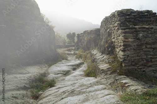 Path in fog. Misty Forest Path. Natural Stone ruin walkway through the Ruins of Schmidtburg. Nostalgic passage through old stone walls of a medieval celtic ruin in Germany, Hunsruck on a foggy day