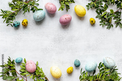 Canvas Print Layout of colorful Easter eggs with spring branches and green leaves, top view