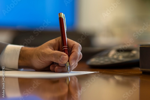 hand of a businessman with a ballpoint pen writing on a sheet