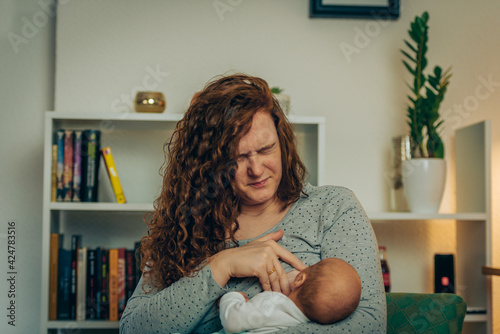 Mother in pain breastfeeding baby photo
