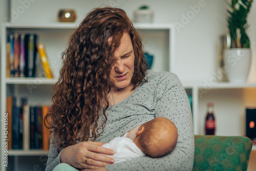 Mother in pain breastfeeding baby photo