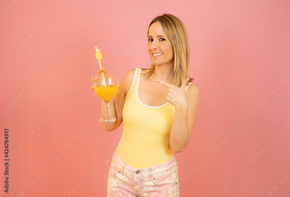 Picture of smiling young woman in swimwear isolated over pink background holding cocktail. Picture of smiling young woman in swimwear isolated over pink background holding cocktail.