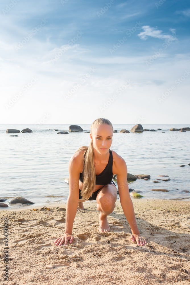 young beautiful sportswoman doing exercises on beach