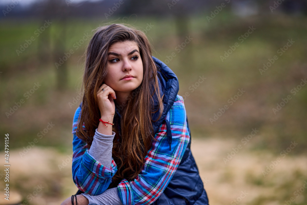 Fototapeta premium portrait of a young woman wearing a hooded jacket with nature in the background